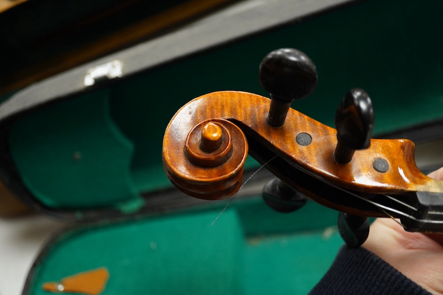 Four cased violins; an early 20th century violin, body 36cm, fitted with a microphone pick up taking a quarter inch jack plug, an early 20th century half size violin, body 32cm, and two student violins. Condition - poor